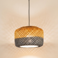 Handcrafted two-tone cane pendant lamp with cylindrical woven design and warm ambient lighting